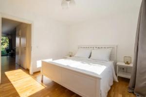 um quarto branco com uma cama branca e piso em madeira em Near Lake Fully Furnished Beautiful Apartment em Viena