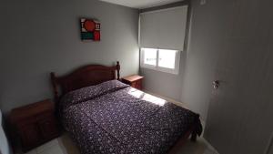 um pequeno quarto com uma cama e uma janela em Apartamento Allegro em Córdova