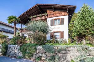 a house with a stone wall and trees at Adang Ferienwohnung Etschtal in Tirolo