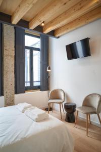 a bedroom with a bed and two chairs and a tv at Brito Capelo 183 in Matosinhos