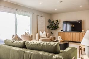sala de estar con sofá verde y TV en @ Marbella Lane - Vibrant & Chic Designer Home, en Fullerton