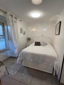 a bedroom with a white bed and a window at L’Atelier de la dépendance in Lempdes sur Allagnon