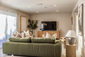 a living room with a green couch and a tv at @ Marbella Lane - Vibrant & Chic Designer Home in Fullerton