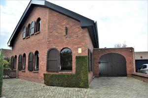 un edificio de ladrillo rojo con garaje negro en Lovely Holiday Home in Merksplas with Fenced Garden, en Merksplas