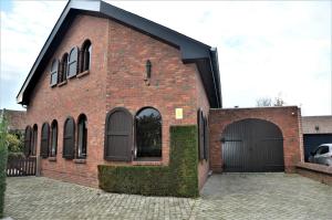 a red brick building with a black garage at Lovely Holiday Home in Merksplas with Fenced Garden in Merksplas