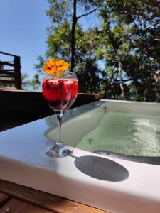 una bebida sentada en una mesa junto a una bañera de hidromasaje en Double Deck - Linda vista com Jacuzzi en Palhoça