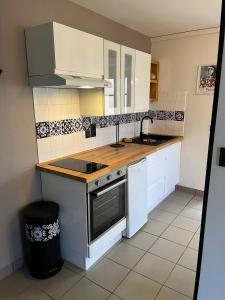 a kitchen with white cabinets and a sink and a stove at L’Atelier de la dépendance in Lempdes sur Allagnon