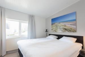 a bedroom with a white bed and a large window at Hello Zeeland - Appartement Beatrixstraat 29 in Domburg