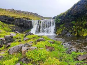 a waterfall on the side of a hill with rocks at Basalt Hotel in Borgarnes