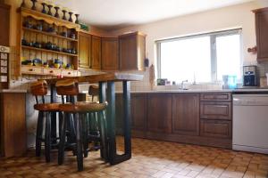 una cocina con armarios de madera y un bar con taburetes en Beautiful House on Wild Atlantic Way - 6 bedrooms en Kenmare