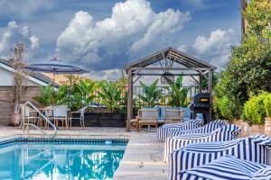 a pool with chairs and an umbrella and a grill at @ Marbella Lane - Vibrant & Chic Designer Home in Fullerton