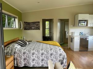 a bedroom with a bed and a kitchen at Chalet Cullen, in Mangawhai