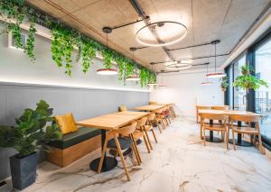 a row of tables and chairs in a room with plants at Luma Terra Prague Hostel in Prague