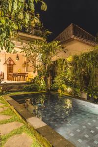 a swimming pool in front of a house at night at Divara Ubud in Ubud