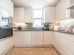 uma cozinha com armários brancos e um lavatório em Pass the Keys Luxurious Flat with Large Private Terrace em Hanworth