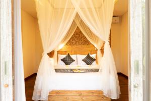 1 dormitorio con cama con dosel y cortinas blancas en Ubud Inn Cottage by Prasi, en Ubud
