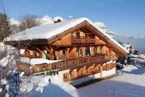 a large wooden house with snow on the roof at Chalet Le Ferme Combloux Rhone-Alps in Combloux