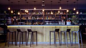 a bar with four stools in front of a counter at Hôtel de Cavoye in Fontainebleau