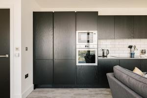 a kitchen with black cabinets and a couch at CitySpace Acton in London