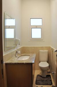 ein Badezimmer mit einem WC und einem Waschbecken sowie zwei Fenster in der Unterkunft Axxodia Mivida Boulevard New cairo in New cairo