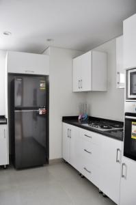 eine Küche mit weißen Schränken und einem schwarzen Kühlschrank in der Unterkunft Axxodia Mivida Boulevard New cairo in New cairo
