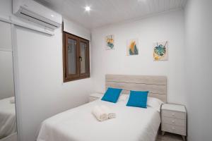 een slaapkamer met een wit bed met blauwe kussens bij Casa Antequeruela in Toledo