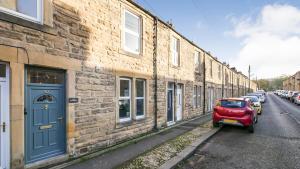 a red car parked next to a brick building at Nala's Nest in Hexham