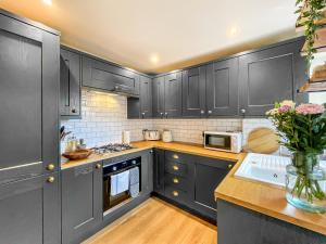 a kitchen with black cabinets and a vase of flowers at Nala's Nest in Hexham +11 photos