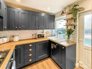 a kitchen with black cabinets and a sink at Nala's Nest in Hexham