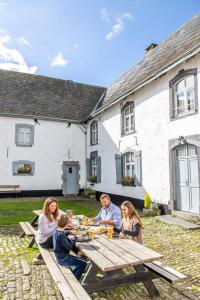 a group of people sitting around a picnic table at Manoir de Sterpigny, château-ferme 17ème siècle gîte la Tour in Gouvy