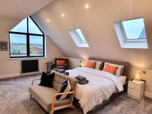 a bedroom with a bed and a couch and windows at Brand New, Stunning Beachside House in Seasalter