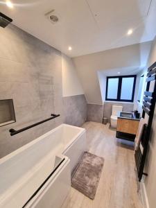 a large bathroom with a tub and a toilet at Brand New, Stunning Beachside House in Seasalter