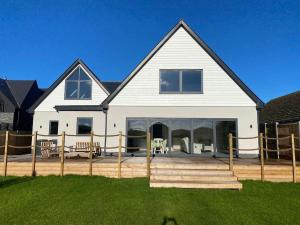 a large white house with a deck in front of it at Brand New, Stunning Beachside House in Seasalter