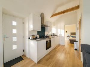 a kitchen with white cabinets and a stove top oven at Skyber Barn, a rural retreat on Bodmin Moor in Liskeard