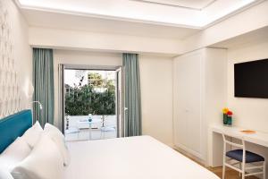 a hotel room with a bed and a desk and a window at Pazziella Garden & Suites in Capri