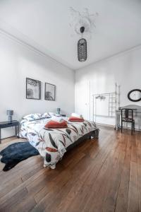a white bedroom with a large bed and wooden floors at Résidence Epinat II - Appartements centre - Parking in Vichy