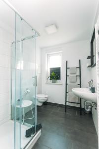 een badkamer met een glazen douche en een wastafel bij Das Schlafgut Dessau in Dessau