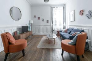 a living room with a blue couch and orange chairs at Résidence Epinat II - Appartements centre - Parking in Vichy
