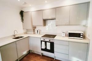 a white kitchen with white cabinets and a microwave at Aldgate Flats in E1. in London