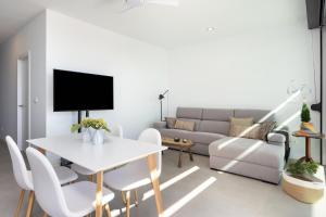 ein Wohnzimmer mit einem weißen Tisch und einem Sofa in der Unterkunft Home2Book Design & Breathtaking Sea Views El Porís in Poris de Abona