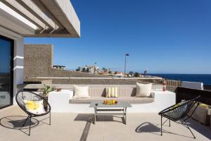 un patio con sofá, sillas y el océano en Home2Book Design & Breathtaking Sea Views El Porís en Poris de Abona
