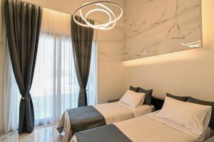 2 Betten in einem Zimmer mit einem Fenster und einem Kronleuchter in der Unterkunft Rihios Hotel in Stavros