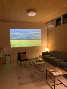 een woonkamer met een bank en een projectiescherm bij Ren chalet in Hakuba