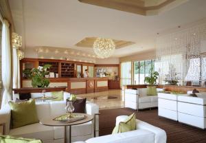 salon z białymi meblami i żyrandolem w obiekcie Hotel Splendid Palace w mieście Limone sul Garda