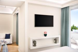 a room with a tv and a bed with a couch at Pazziella Garden & Suites in Capri