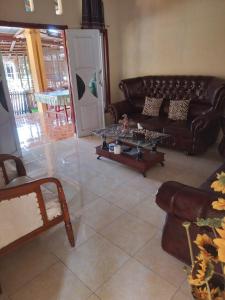 a living room with a leather couch and a table at FRANGKY HOMESTAY in Manado