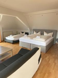 twee bedden in een kamer met een bank bij Hotel Hofmann Zur Mühle in Bad Krozingen