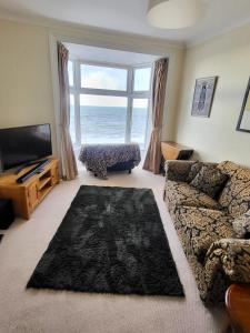 a living room with a couch and a large window at Stunning Aberystwyth South Beach Apartment in Aberystwyth