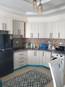 a kitchen with white cabinets and a black refrigerator at Sharm Hills in Sharm El Sheikh