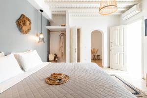 a white bedroom with a large bed with a plate of food on it at Haka Suites Mykonos Town in Mikonos
